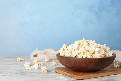 Wooden bowl with tasty popcorn on table. Space for text