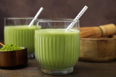 Photo of Glass of tasty matcha smoothie with straw on wooden table, closeup