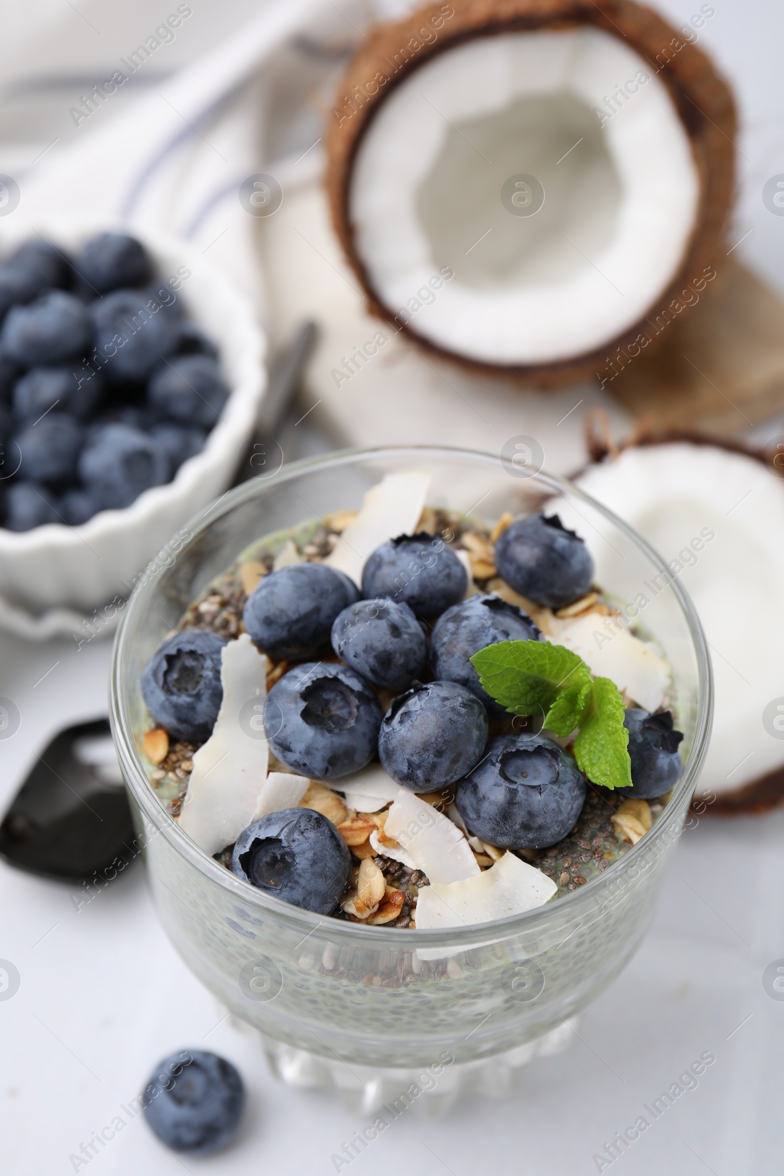 Photo of Tasty chia matcha pudding with coconut and blueberries on white table, above view. Healthy breakfast