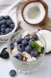 Photo of Tasty chia matcha pudding with coconut and blueberries on white table, above view. Healthy breakfast