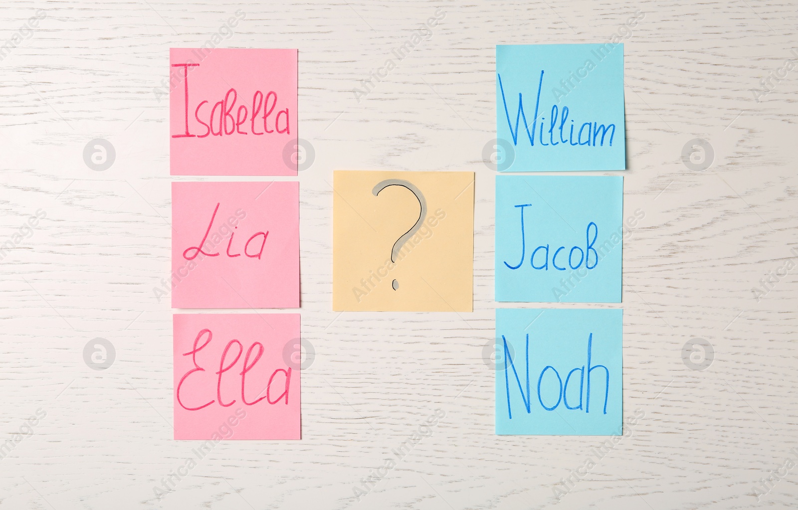 Photo of Colorful sticky notes with written baby names on white wooden background, flat lay