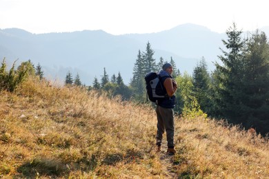 Photo of Tourist with backpack in mountains on sunny day. Space for text