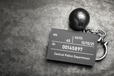 Photo of Metal ball with chain and mugshot letter board on grey table, flat lay. Space for text