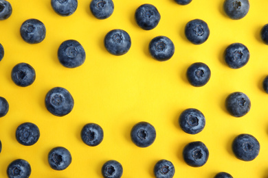 Frame of fresh ripe blueberries on yellow background, flat lay. Space for text