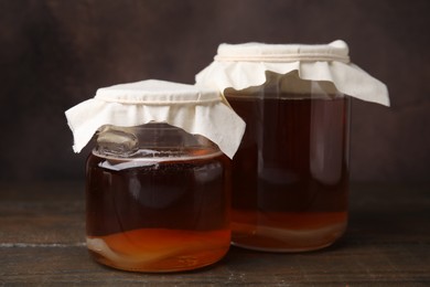 Tasty kombucha in glass jars on wooden table