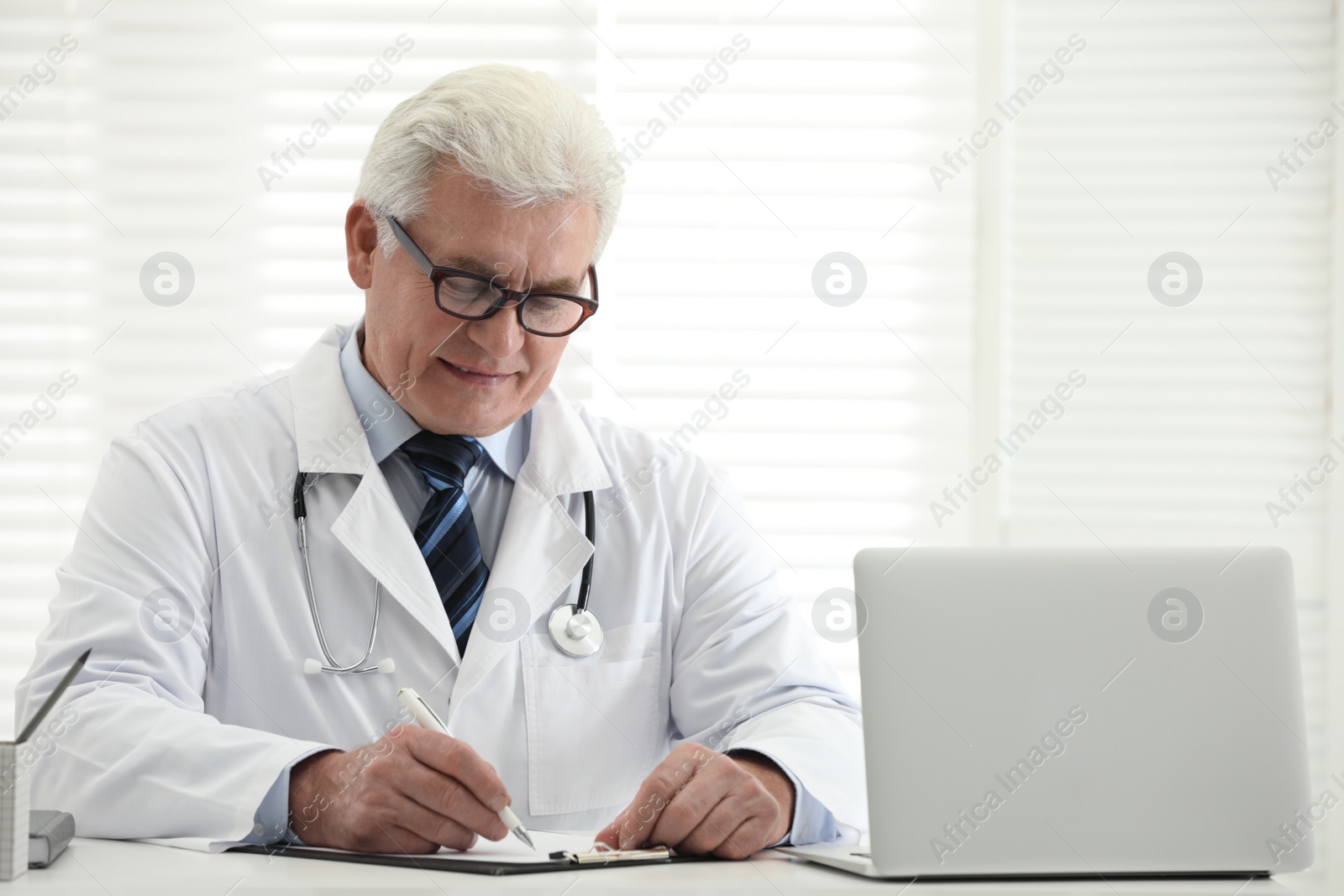 Photo of Senior doctor working at table in office