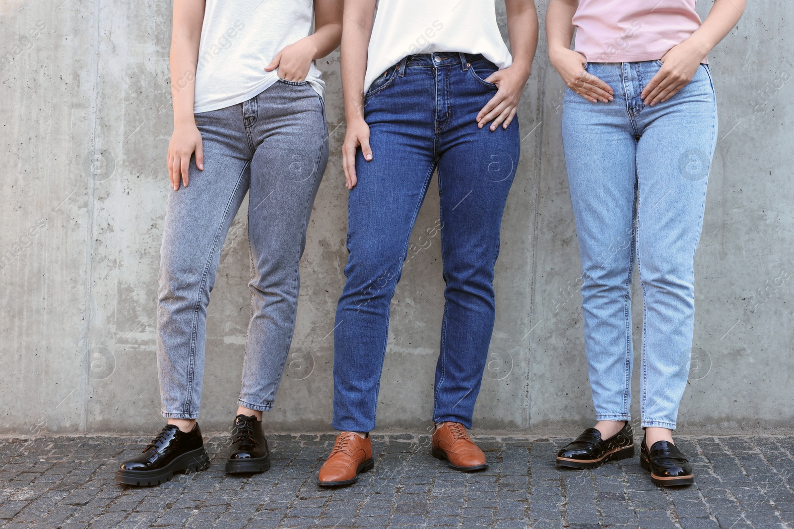 Photo of Women in stylish jeans near grey wall outdoors, closeup