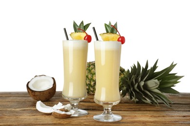 Photo of Tasty Pina Colada cocktail and ingredients on wooden table against white background