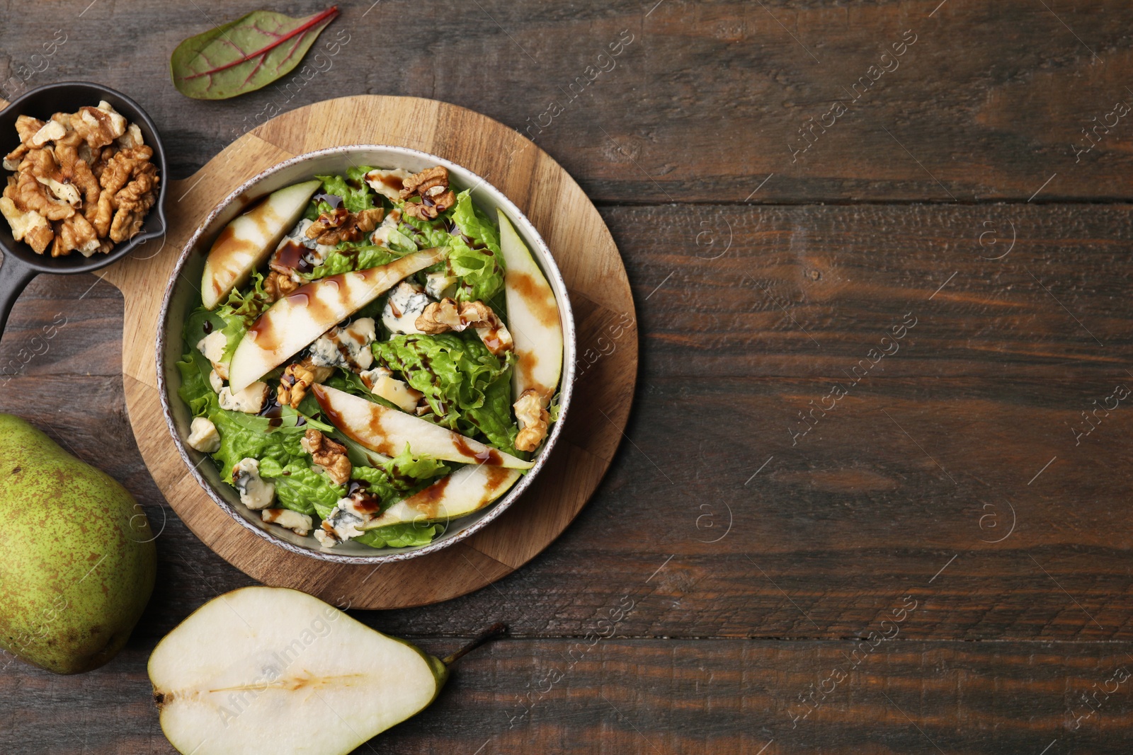 Photo of Delicious pear salad with sauce in bowl and ingredients on wooden table, flat lay. Space for text