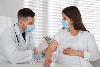 Doctor vaccinating pregnant woman against Covid-19 in clinic