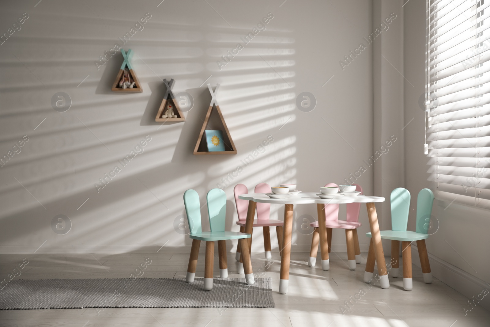 Photo of Small table and chairs with bunny ears indoors. Children's room interior