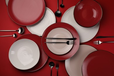 Stylish table setting with cutlery on red background, flat lay
