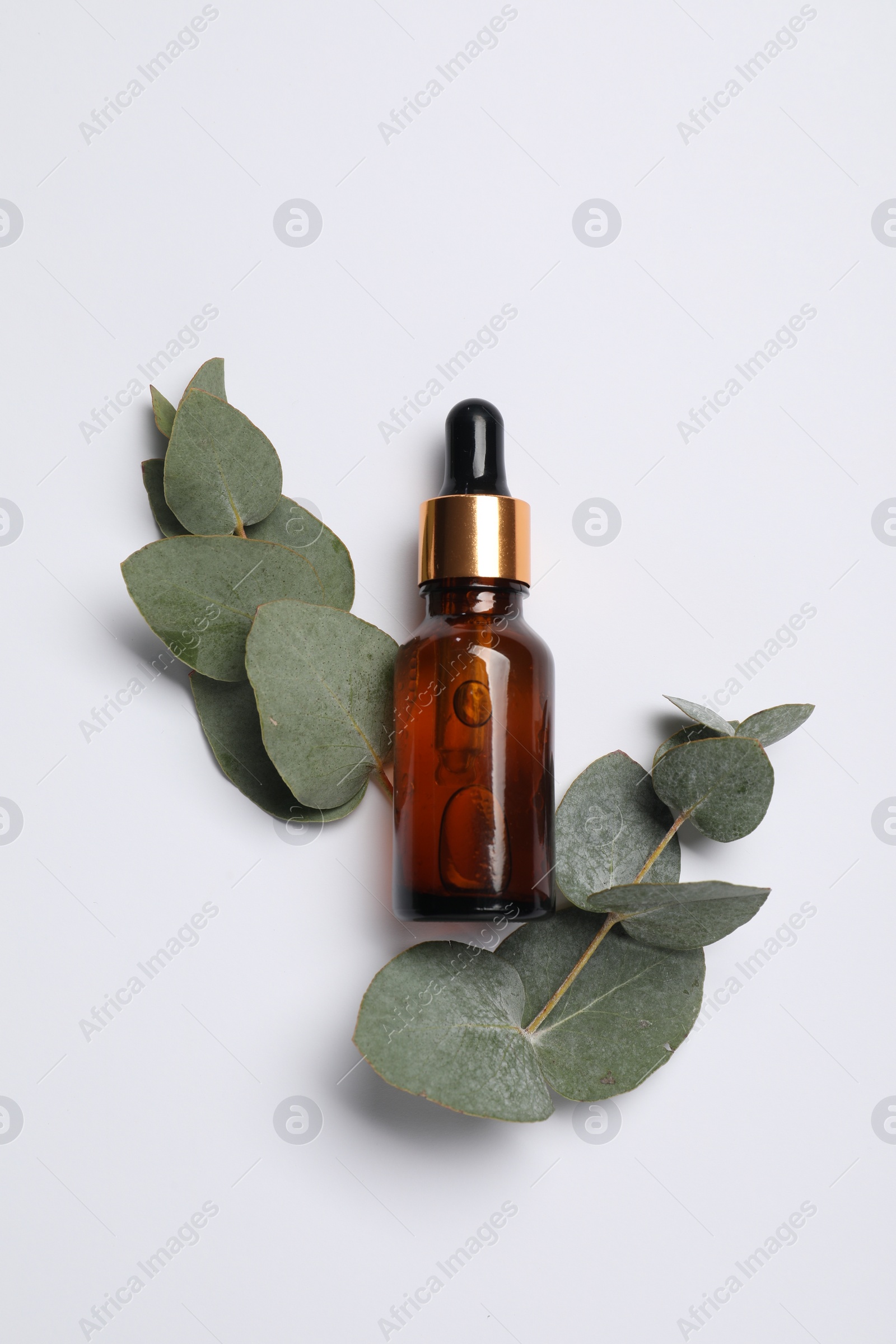 Photo of Aromatherapy product. Bottle of essential oil and eucalyptus leaves on white background, flat lay