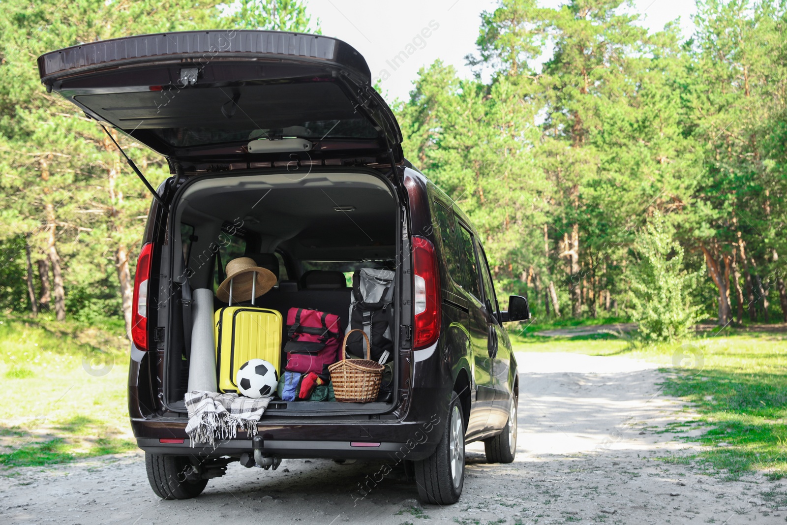 Photo of Van with camping equipment in trunk outdoors