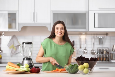 Young woman preparing tasty healthy smoothie at table in kitchen