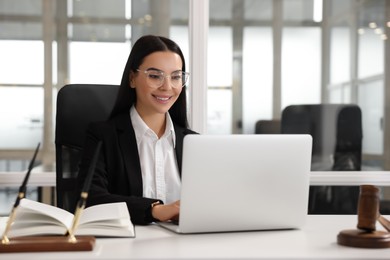 Photo of Smiling lawyer working on laptop in office