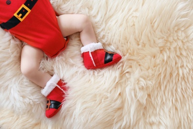 Photo of Cute baby in Christmas costume lying on fur rug