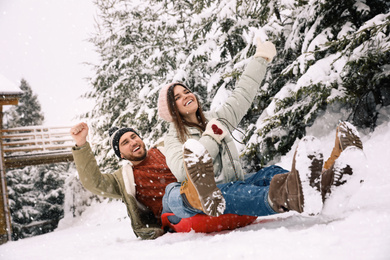 Happy couple having fun together outdoors on snowy day. Winter vacation