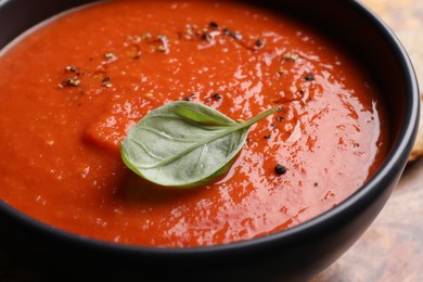 Photo of Delicious tomato cream soup in bowl on table, closeup