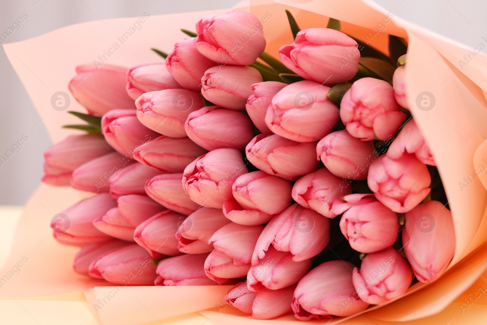 Photo of Bouquet of beautiful pink tulips on beige background, closeup