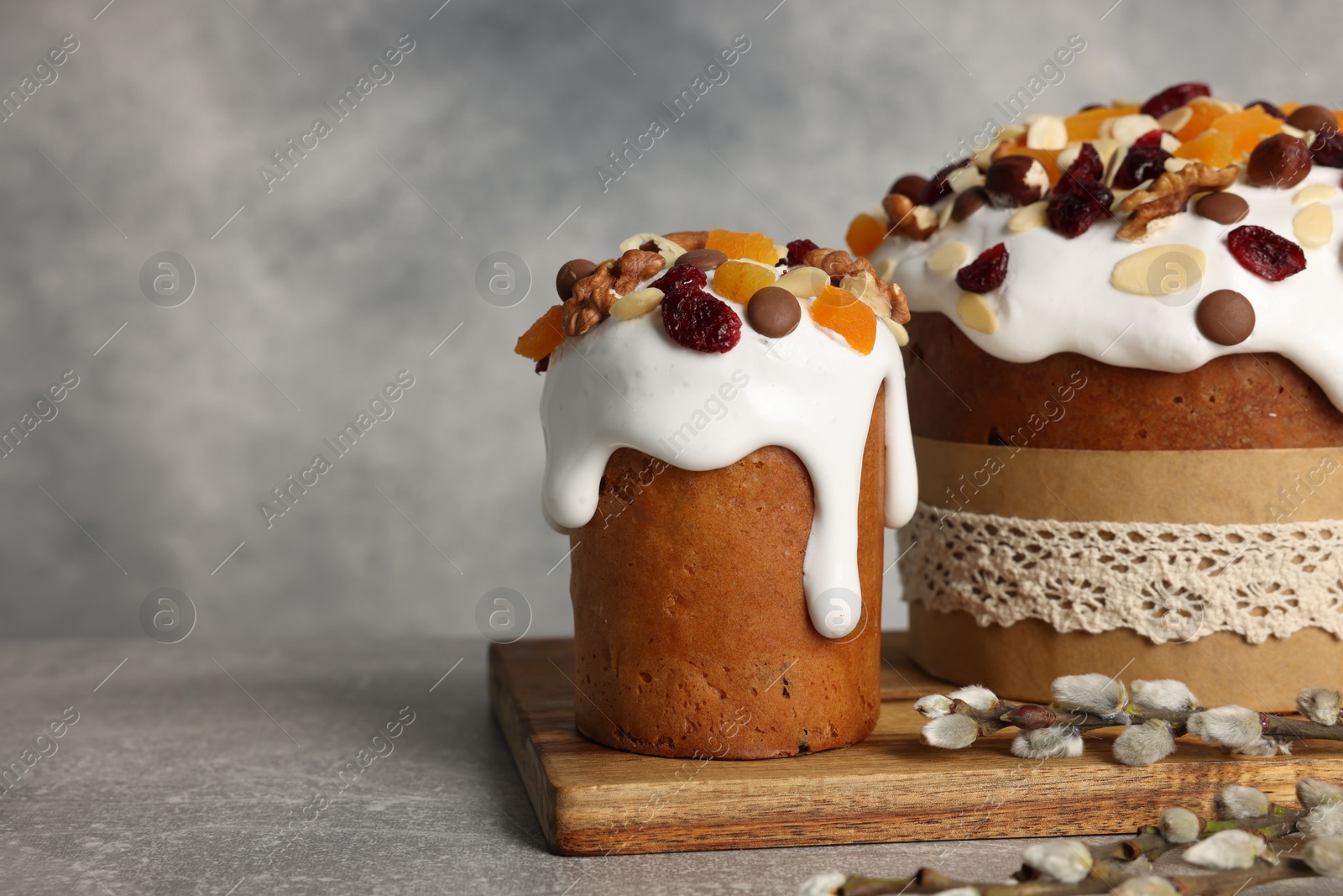 Photo of Tasty Easter cakes and willow branches on grey table. Space for text