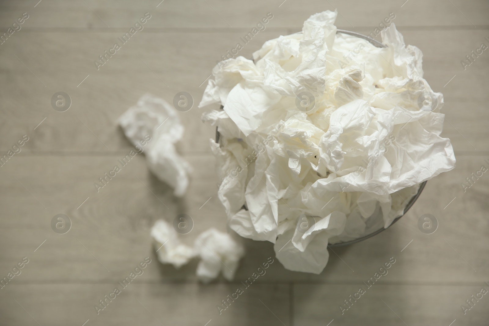 Photo of Used paper tissues and trash can on wooden floor, flat lay