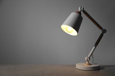 Photo of Stylish modern desk lamp on light gray table, space for text