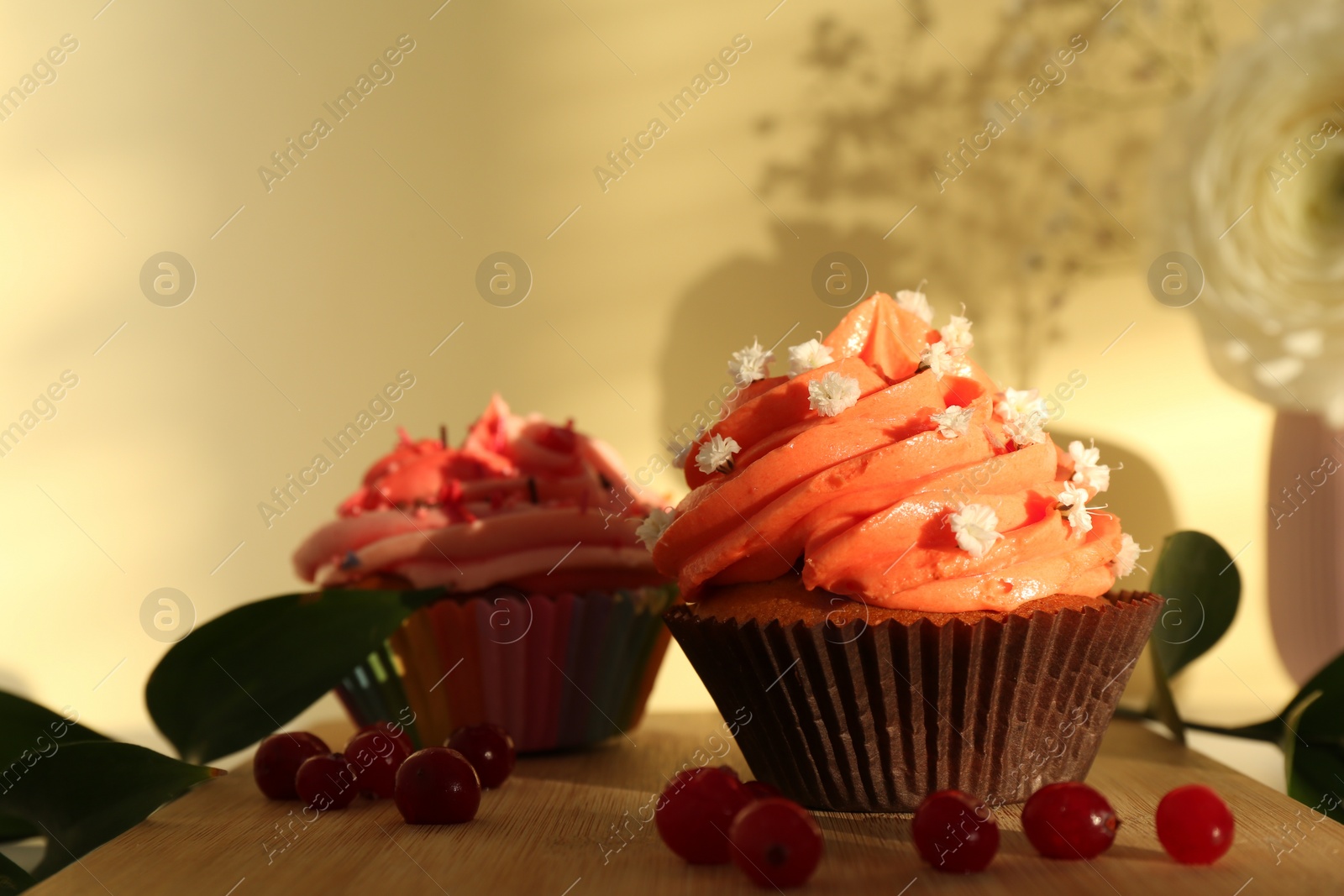 Photo of Delicious cupcake with bright cream and flowers on wooden table