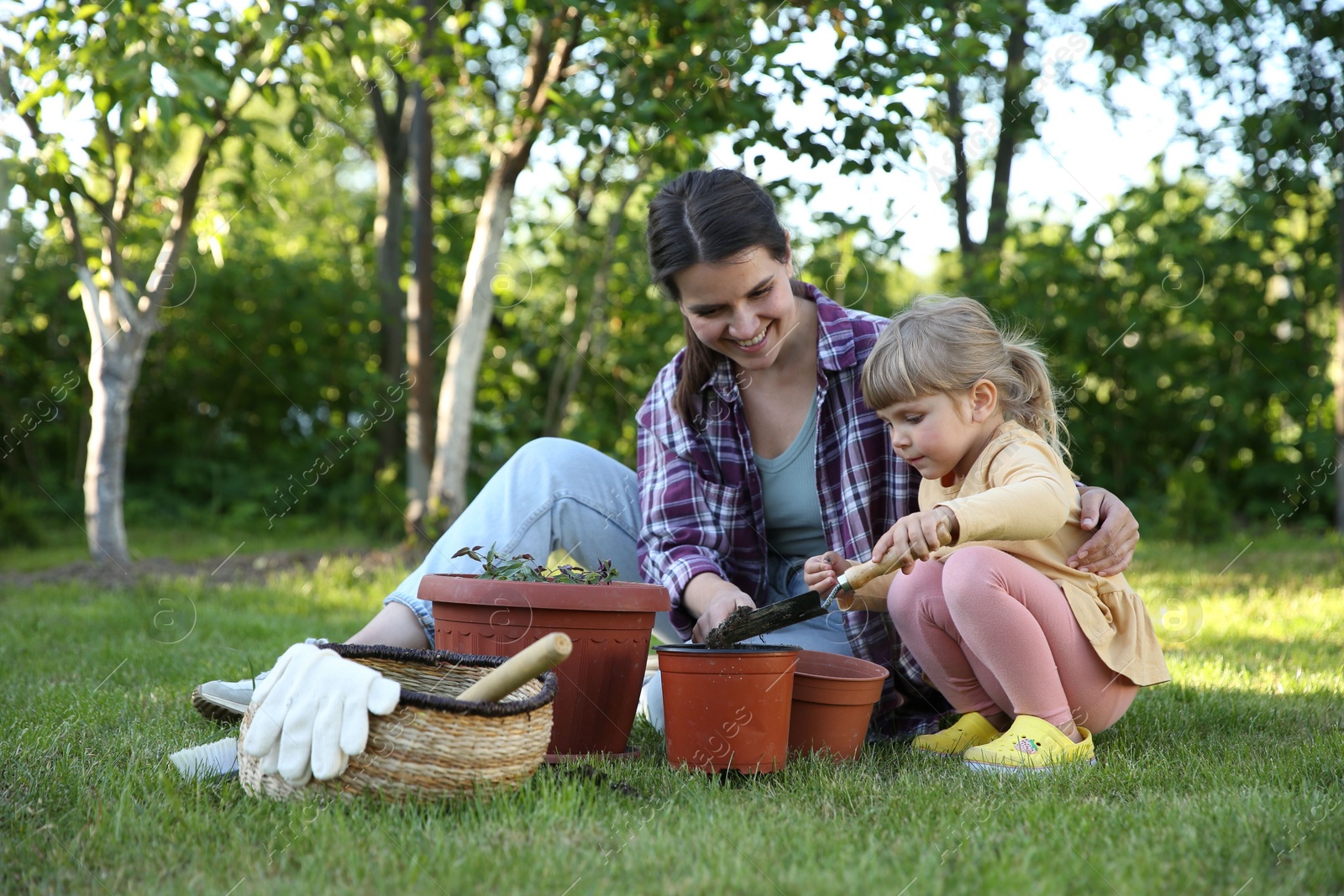 Photo of Mother and her daughter planting tree together in garden