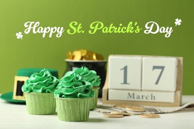 Image of Happy St. Patrick's day card. Cupcakes, pot of gold and wooden block calendar with date - March 17 on white table