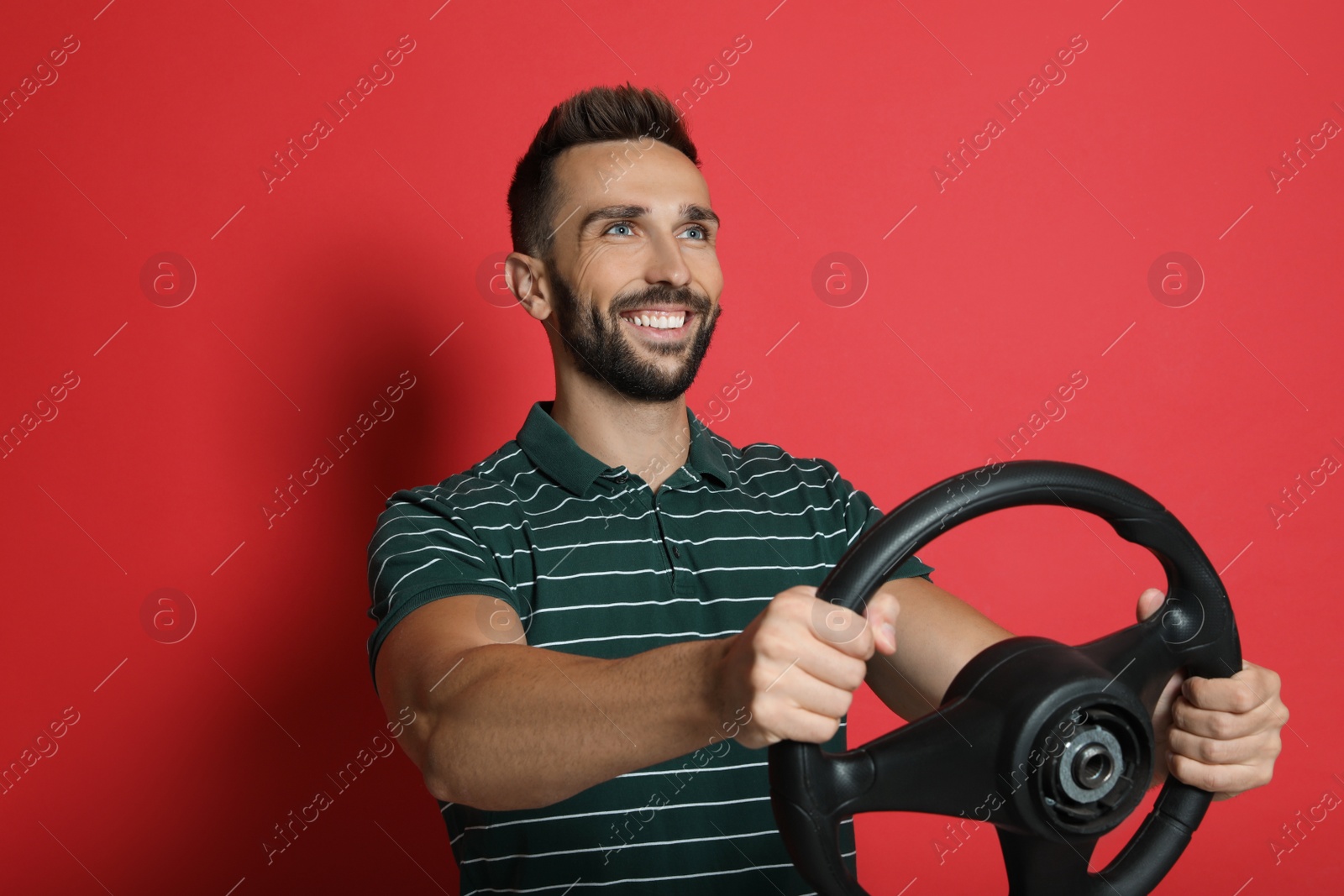 Photo of Happy man with steering wheel on red background