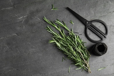 Flat lay composition with fresh rosemary twigs and scissors on grey table. Space for text