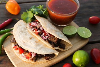 Photo of Delicious tacos with meat, vegetables and sauce on wooden table