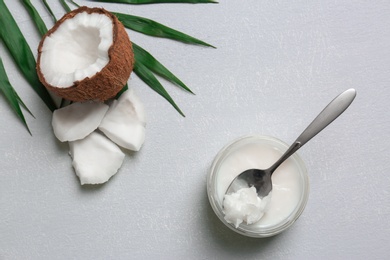 Photo of Jar with coconut oil and nut pieces on grey background