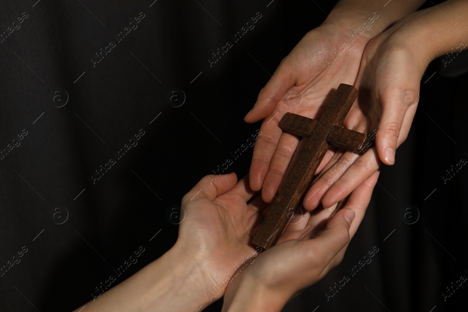 Photo of Easter - celebration of Jesus resurrection. Women holding wooden cross on dark background, closeup. Space for text