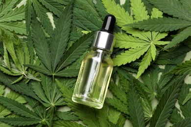Photo of Bottle of CBD oil or THC tincture on fresh hemp leaves, top view