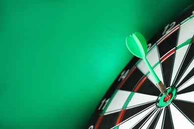 Arrow hitting target on dart board against green background