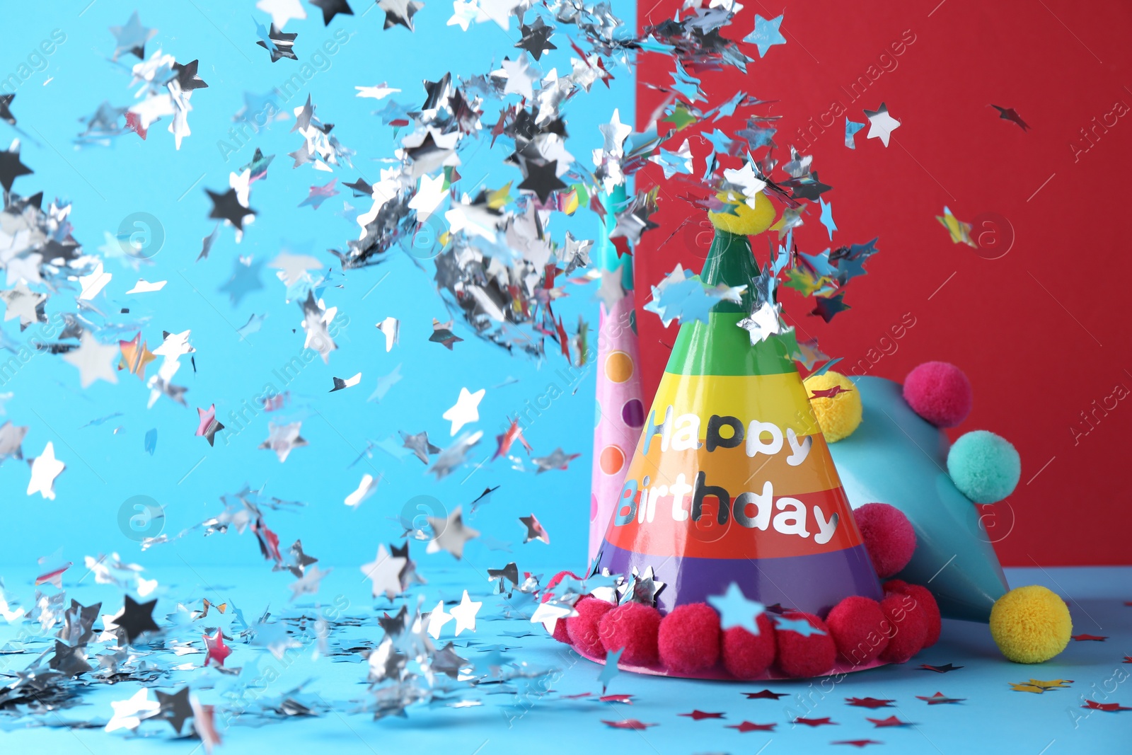 Photo of Party hats and confetti on color background, space for text