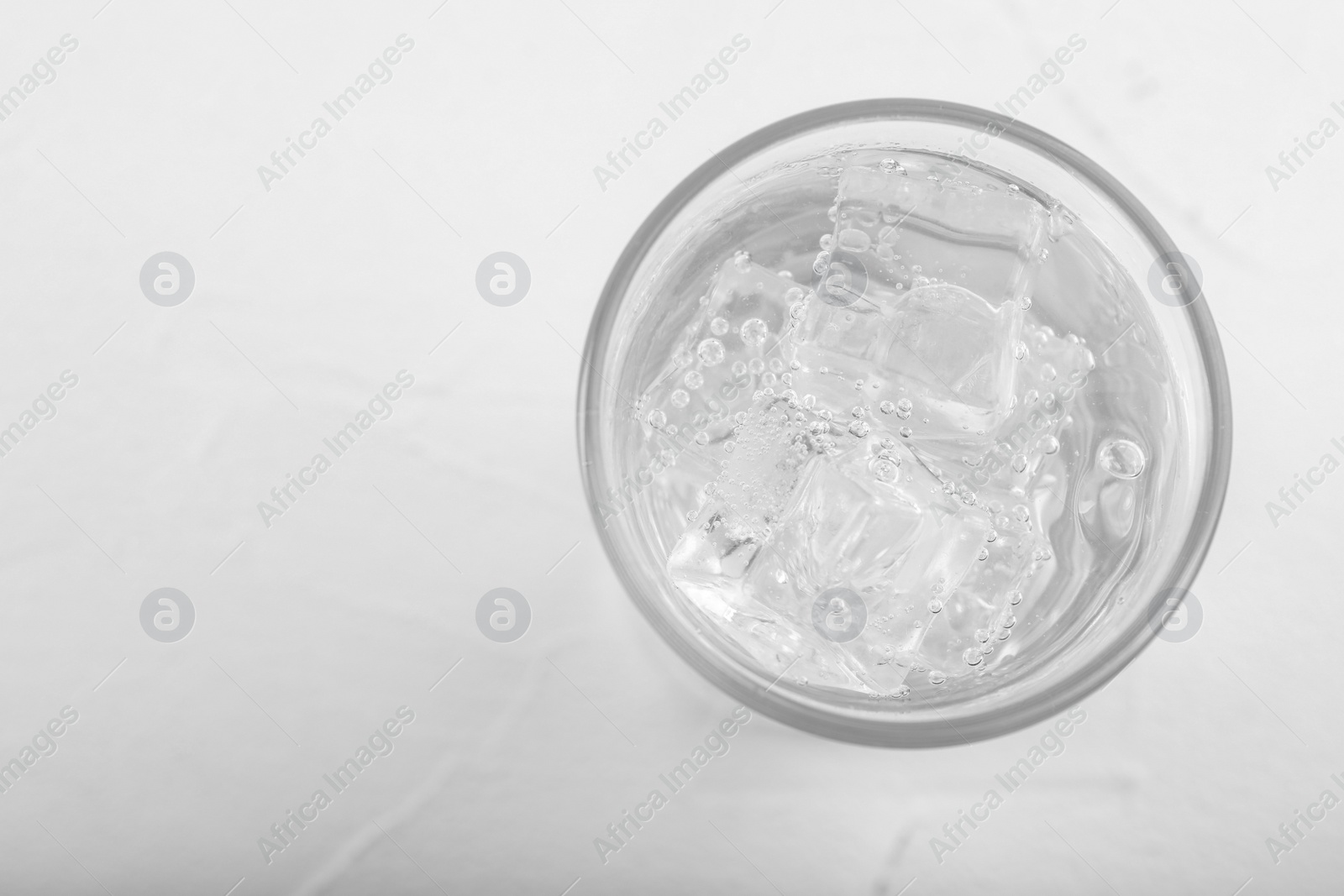 Photo of Glass of soda water on white table, top view. Space for text