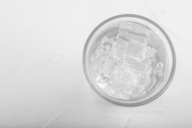 Glass of soda water on white table, top view. Space for text