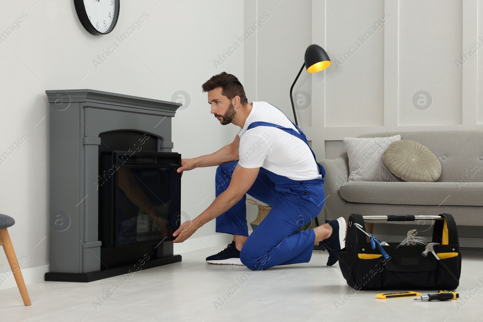 Photo of Professional technician installing electric fireplace in room