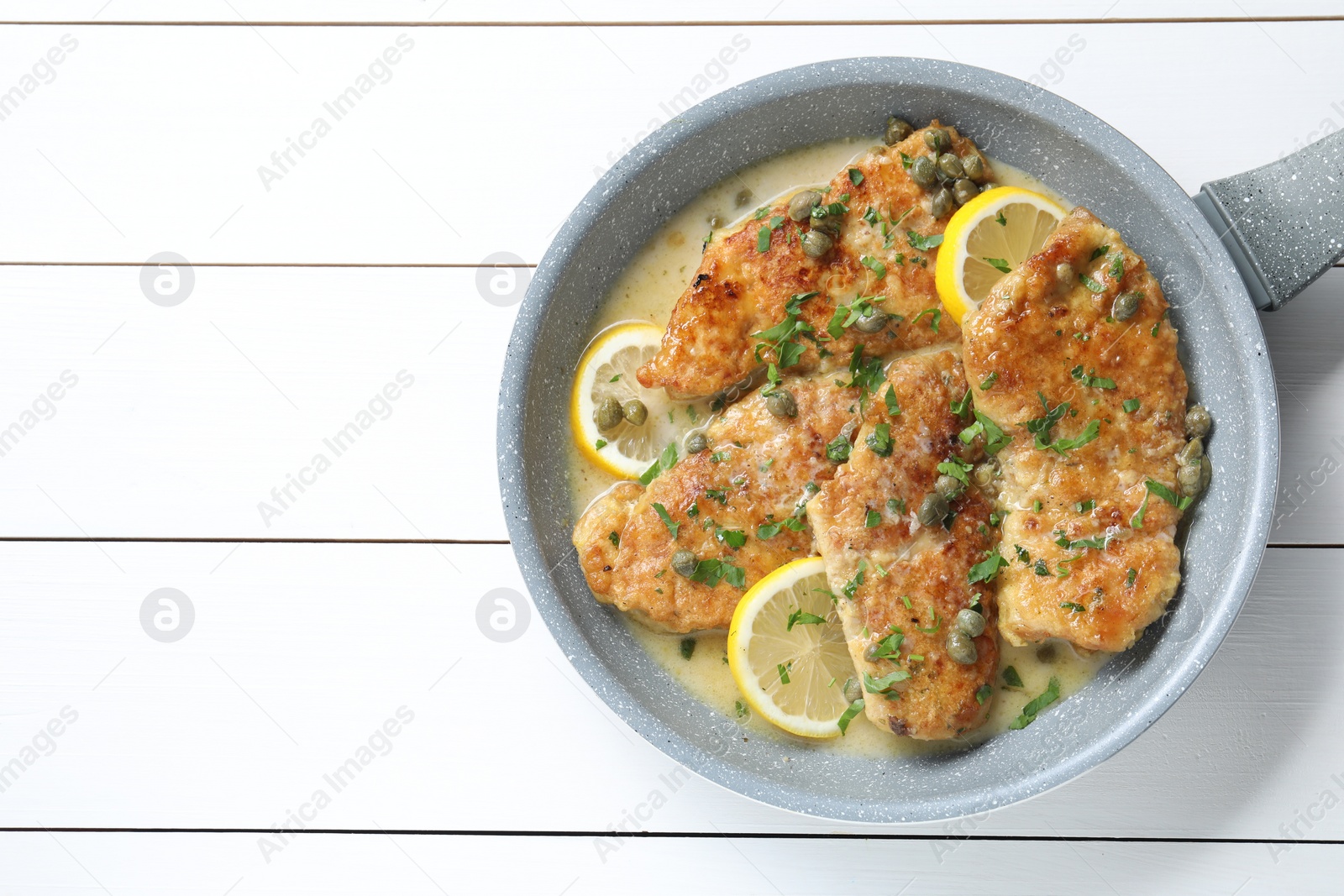 Photo of Delicious chicken piccata on white wooden table, top view. Space for text