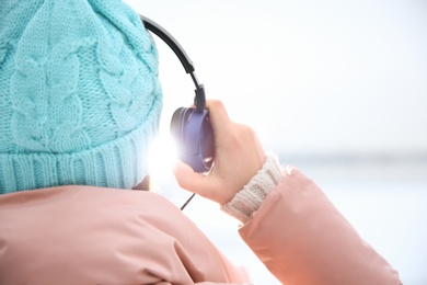 Photo of Young woman listening to music with headphones outdoors, closeup