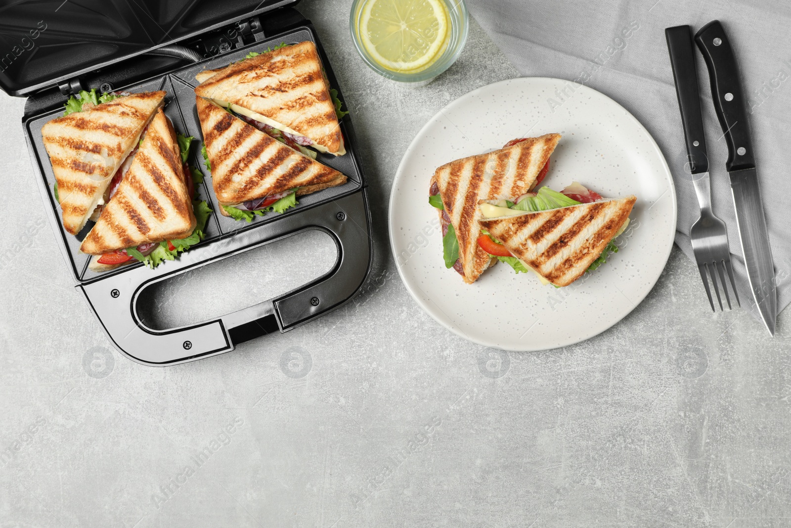 Photo of Flat lay composition with modern sandwich maker and breakfast served on grey table, space for text