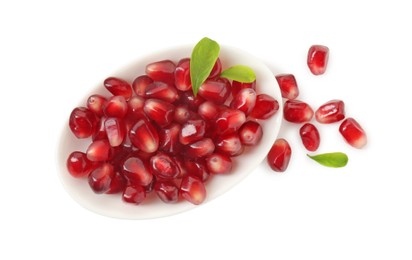 Photo of Ripe juicy pomegranate grains and leaves in bowl isolated on white