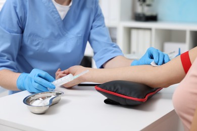 Laboratory testing. Doctor taking blood sample from patient at white table in hospital, closeup