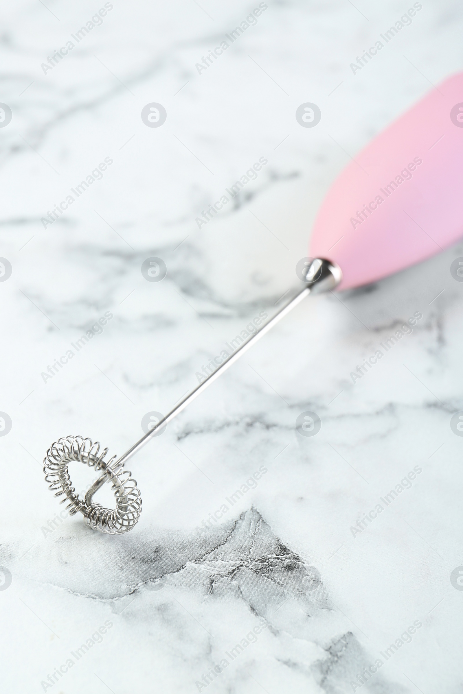 Photo of Pink milk frother wand on white marble table, closeup