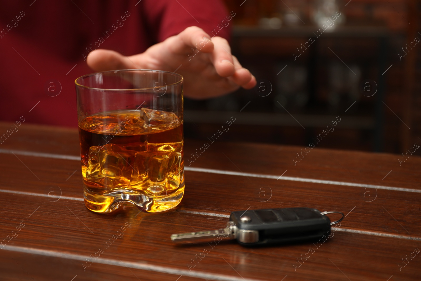 Photo of Man reaching for alcoholic drink at table with car keys, closeup. Don't drink and drive concept