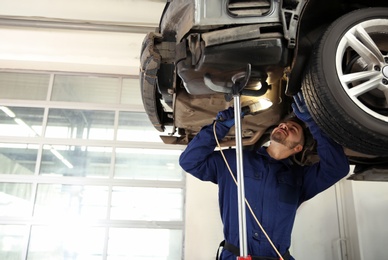 Technician checking modern car at automobile repair shop