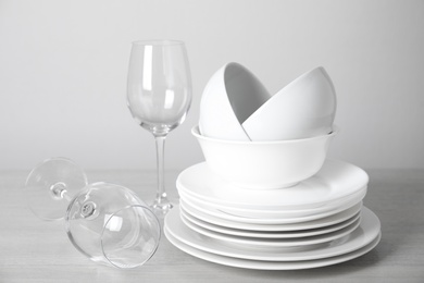 Photo of Clean plates, bowls and glasses on table against white background